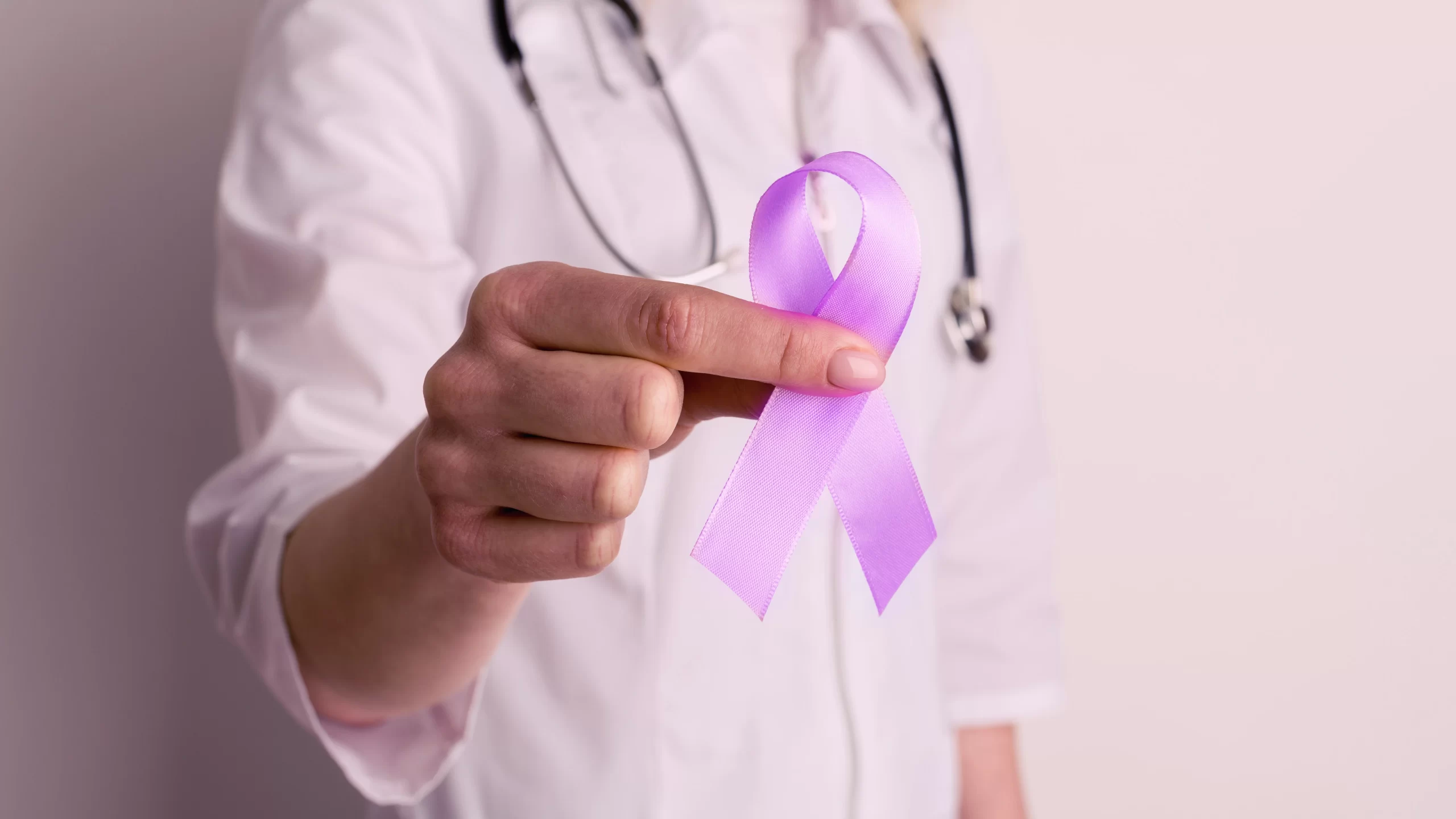 Doctor holding a lavender cancer awareness ribbon symbolizing cancer care and support at Zanish Cancer Hospital, Ahmedabad.